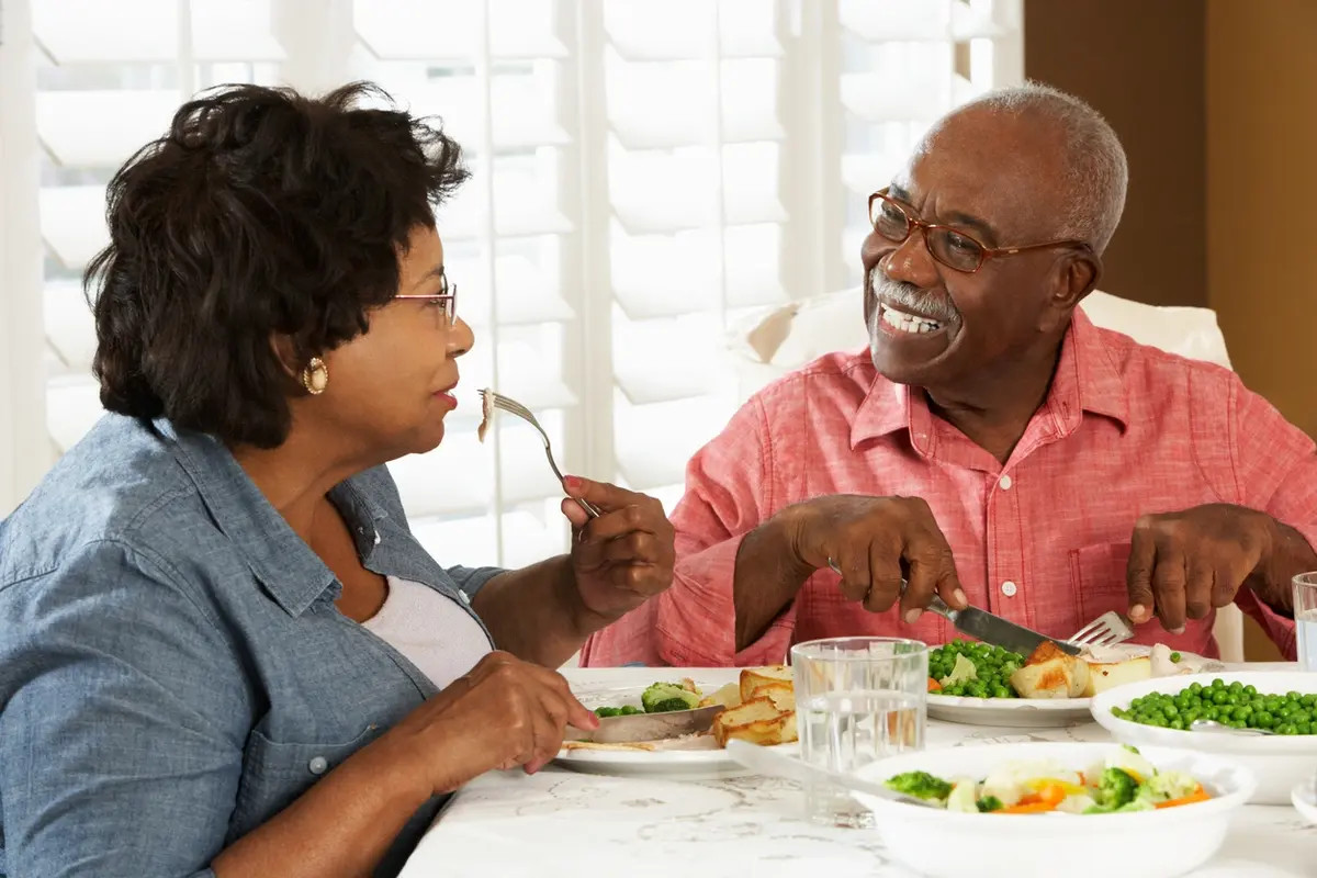 couple-dining-and-discussing-assisted-living-myths-at-pioneer-village Two older adults enjoying a shared meal and conversation about assisted living myths at Pioneer Village in Jacksonville, OR, highlighting social connection in assisted living.
